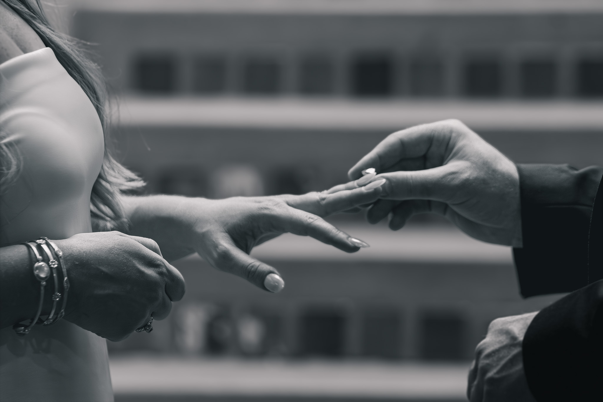 Close-up black and white photograph of a groom placing a ring on his bride's finger during their Denver courthouse ceremony