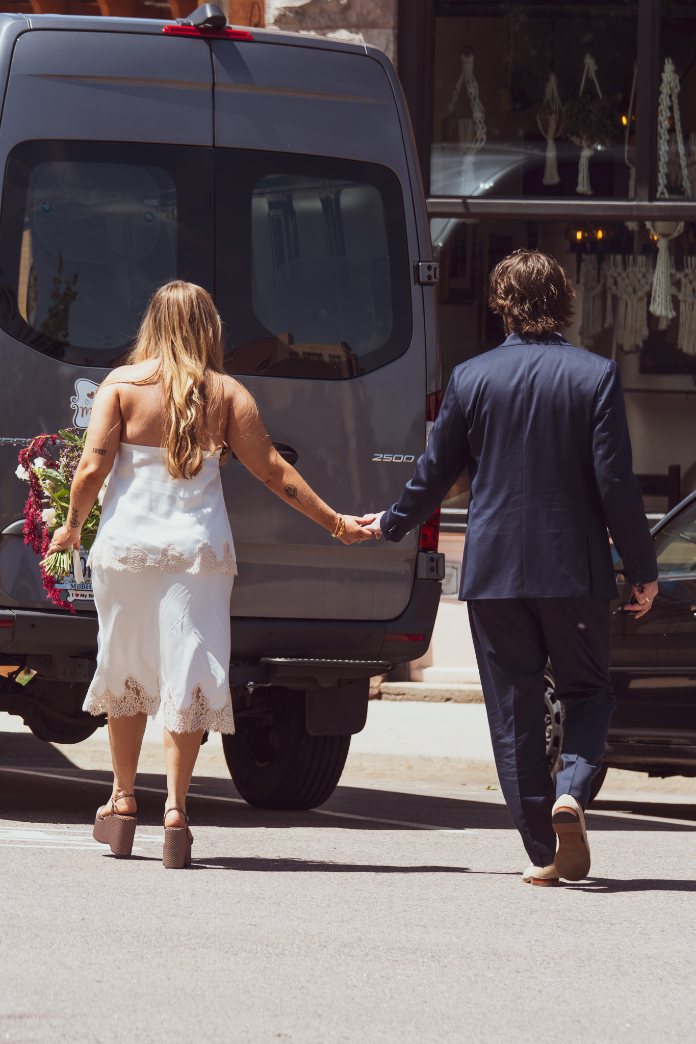 Bride and groom walking hand-in-hand through the streets of Denver after their elopement, backs to camera