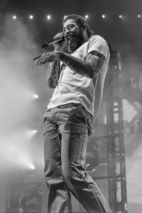 A black-and-white concert photo of a singer mid-song in a spotlight