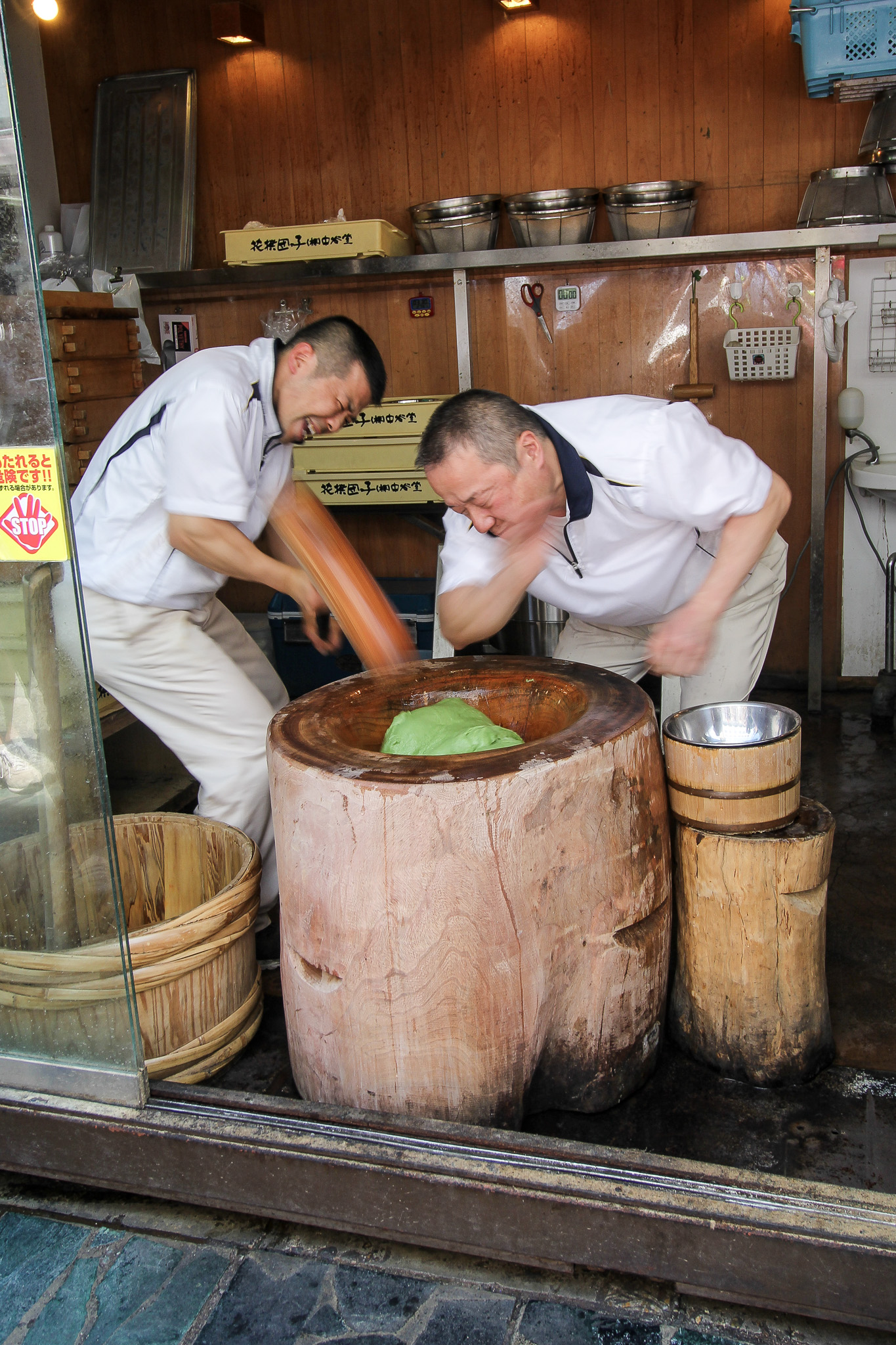 Workers preparing mochi with a traditional wooden mortar in Japan