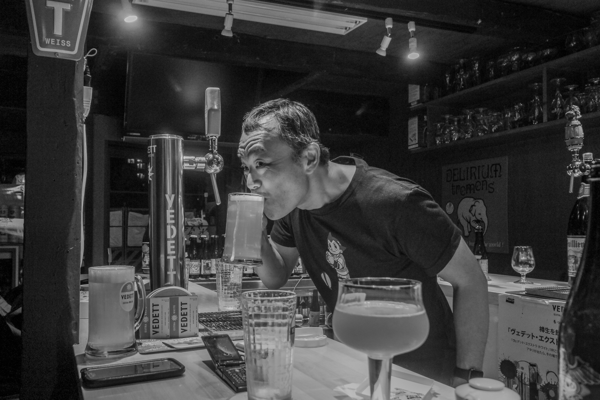 Man enjoying an overflowing drink at a craft beer bar in Japan