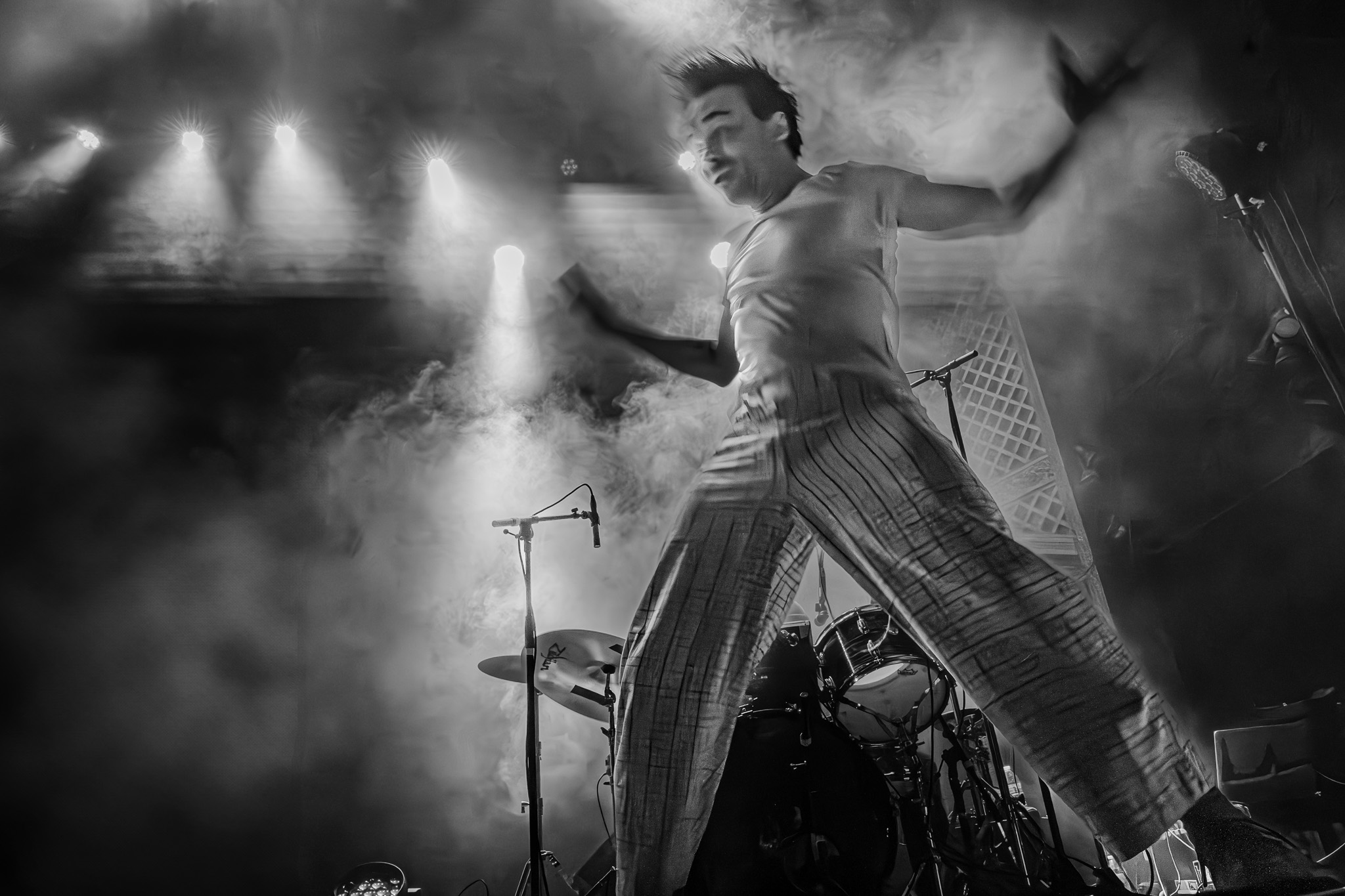 Performer jumping mid-air through stage smoke at a live music show